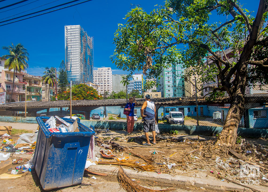 Dos personas conversan en el Vedado, cerca de una acumulación de basura. Foto: Otmaro Rodríguez.