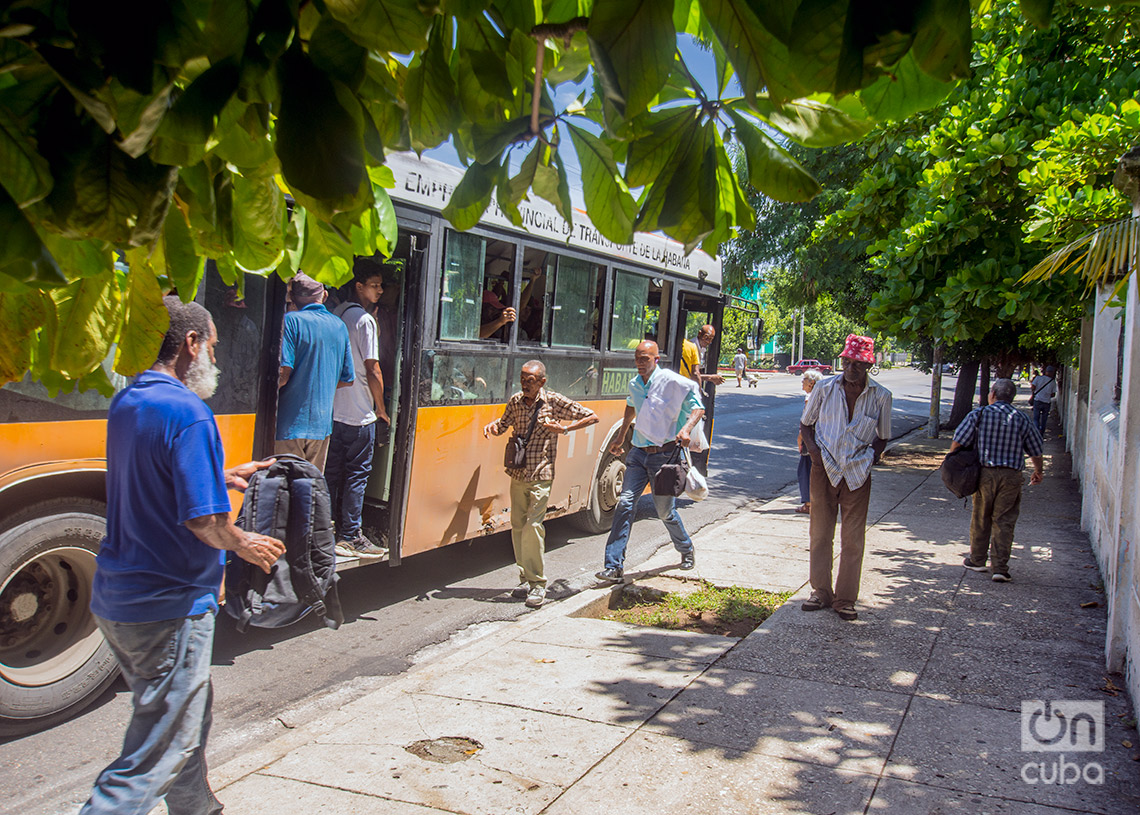 Personas caminan y suben a una guagua en la calle 23 del Vedado. Foto: Otmaro Rodríguez.