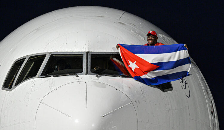 El luchador cubano Mijaín López, cinco veces campeón olímpico, sostiene una bandera de Cuba en la ventanilla del piloto a su llegada este lunes al aeropuerto José Martí de La Habana luego de participar en los Juegos Olímpicos de París 2024. Foto: Adalberto Roque / POOL / AFP vía EFE.