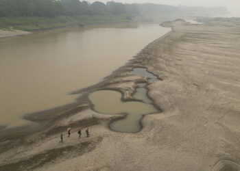 Pescadores cruzando un banco de arena ocasionado por la sequía en el río Madeira, en Porto Velho, estado de Rondonia Foto: Isaac Fontana/EFE.