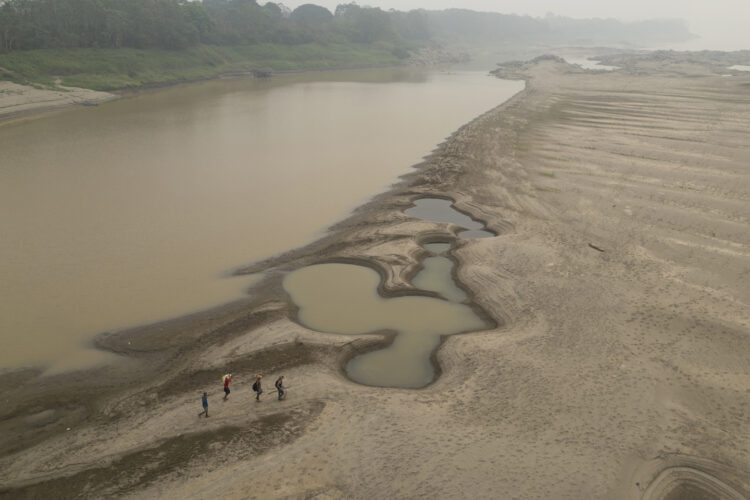 Pescadores cruzando un banco de arena ocasionado por la sequía en el río Madeira, en Porto Velho, estado de Rondonia Foto: Isaac Fontana/EFE.