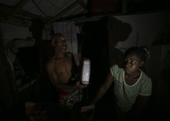 Víctor y Catalina muestran una lámpara led rota mientras hablan con EFE en su casa durante un apagón, en el poblado de Santa Marta, Varadero, en marzo de 2024. Foto: Yander Zamora/EFE.