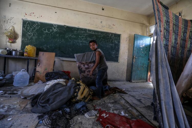 Un niño palestino inspecciona el refugio de su familia en una escuela administrada por la UNRWA. Foto: MOHAMMED SABER/EFE/EPA.