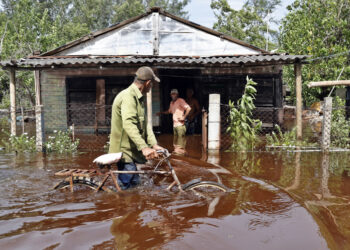 Un hombre camina con una bicicleta por una calle inundada de agua del mar tras el paso del huracán Helene, en el poblado de Guanímar, en la costa sur de la provincia cubana de Artemisa. Foto: Ernesto Mastrascusa / EFE.