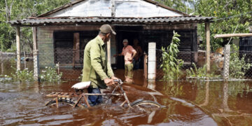 Un hombre camina con una bicicleta por una calle inundada de agua del mar tras el paso del huracán Helene, en el poblado de Guanímar, en la costa sur de la provincia cubana de Artemisa. Foto: Ernesto Mastrascusa / EFE.