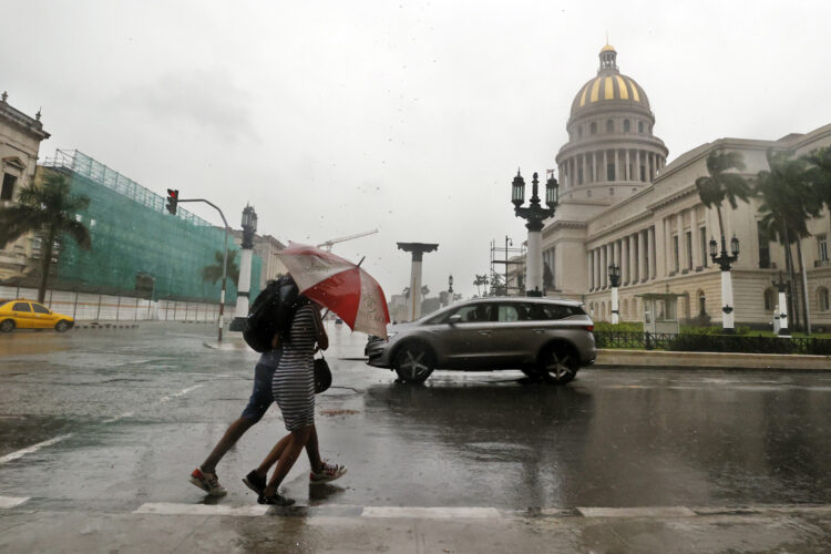 Personas bajo la lluvia en La Habana. Foto: Ernesto Mastrascusa / EFE / Archivo.