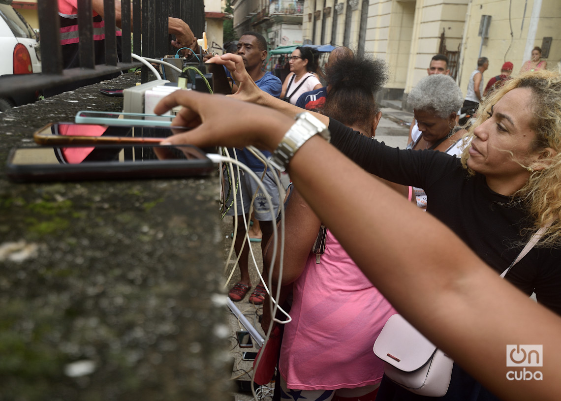 Personas recargan sus teléfonos en La Habana durante el apagón por la desconexión total del sistema eléctrico de Cuba. Foto: Otmaro Rodríguez.