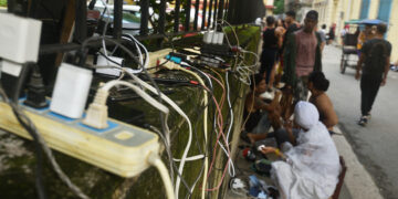 Personas recargan sus teléfonos en La Habana durante el apagón por la desconexión total del sistema eléctrico de Cuba. Foto: Otmaro Rodríguez.