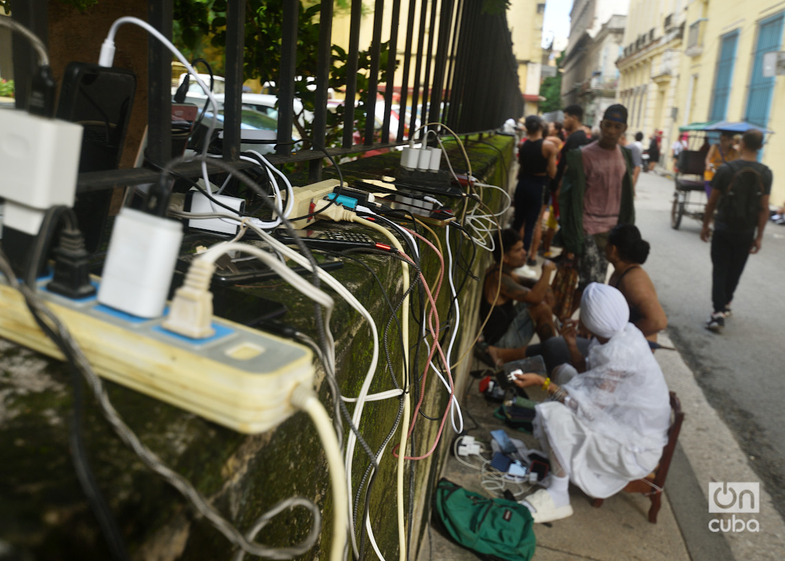 Personas recargan sus teléfonos en La Habana durante el apagón por la desconexión total del sistema eléctrico de Cuba. Foto: Otmaro Rodríguez.