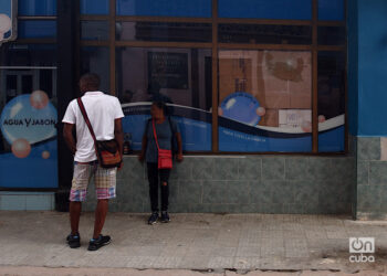 Personas en las afueras de una tienda de La Habana con la vidriera rota durante el apagón por la desconexión total del sistema eléctrico de Cuba. Foto: Otmaro Rodríguez.