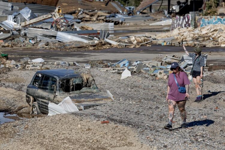 Personas caminando junto a un vehículo luego de las inundaciones provocadas por la tormenta tropical Helene en Asheville, Carolina del Norte. Foto: EFE/EPA Erik S. Lesser.