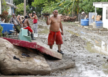 Un hombre camina junto a colchones destruidos en el exterior de una vivienda en la región de San Antonio del Sur una semana después del paso de la tormenta tropical Oscar. Foto: Ernesto Mastrascusa / POOL / EFE.