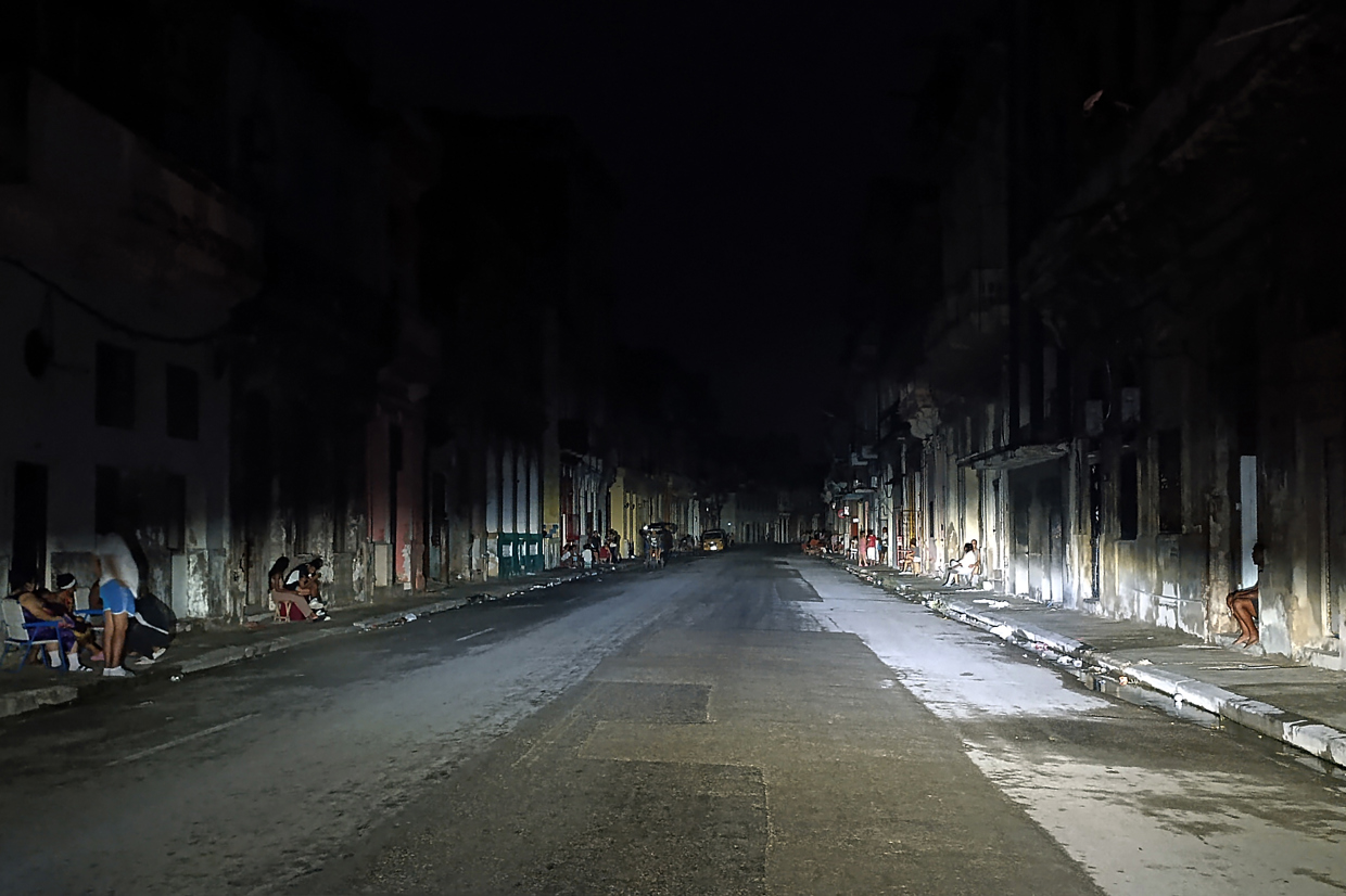 Personas de noche en una calle de La Habana durante el apagón por la desconexión total del sistema eléctrico de Cuba. Foto: Ernesto Mastrascusa / EFE.