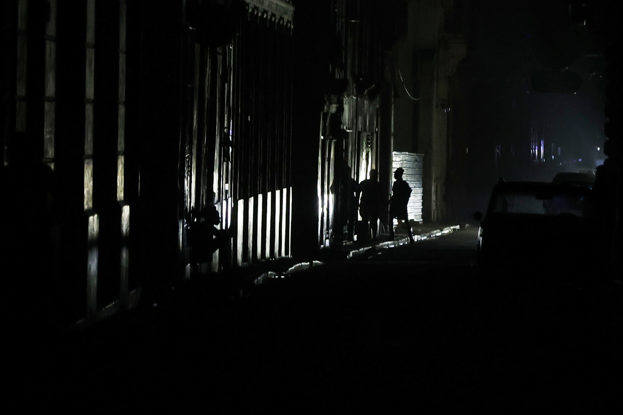 Personas caminan de noche en una calle de La Habana durante durante el apagón por la desconexión total del sistema eléctrico de Cuba. Foto: Ernesto Mastrascusa / EFE.