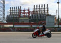 Un hombre en una moto eléctrica pasa frente a una de las plantas de generación eléctrica en el puerto de La Habana Foto: Ernesto Mastrascusa / EFE / Archivo.