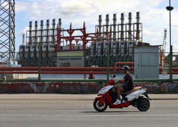 Un hombre en una moto eléctrica pasa frente a una de las plantas de generación eléctrica que permanece este domingo, en el puerto de La Habana Foto: EFE/ Ernesto Mastrascusa