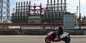 Un hombre en una moto eléctrica pasa frente a una de las plantas de generación eléctrica en el puerto de La Habana Foto: Ernesto Mastrascusa / EFE / Archivo.