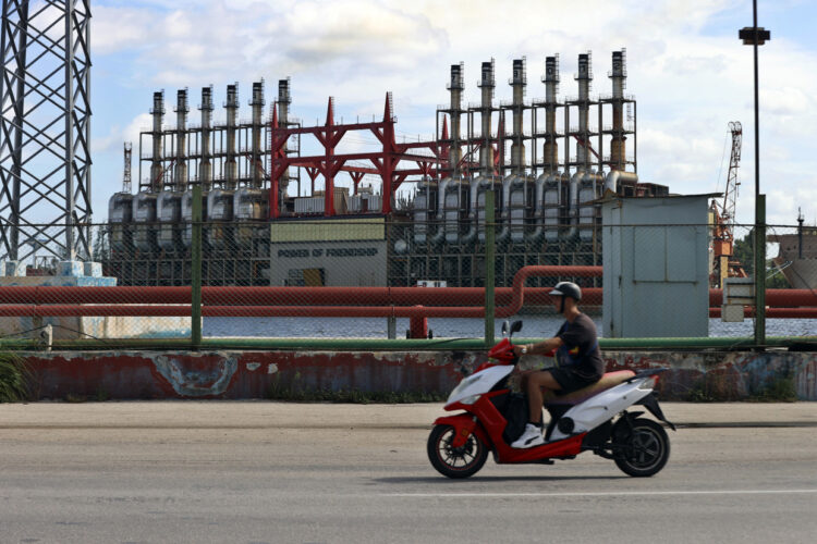 Un hombre en una moto eléctrica pasa frente a una de las plantas de generación eléctrica que permanece este domingo, en el puerto de La Habana Foto: EFE/ Ernesto Mastrascusa