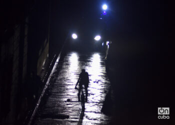 Un ciclista iluminado por las luces de un auto en La Habana durante el apagón general provocado por el huracán Rafael. Foto: Otmaro Rodríguez.