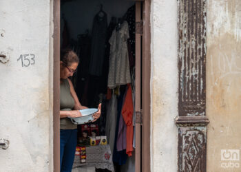 Una mujer limpia un arroz para cocinar, junto a un puesto de venta particular, a la entrada de su casa. Foto: Kaloian / Archivo.