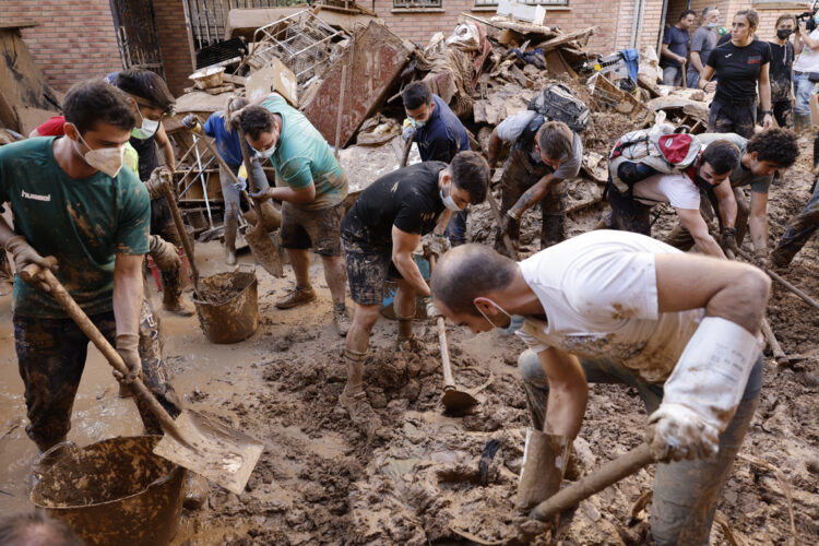 Varias personas retiran el lodo acumulado en una calle de la localidad valenciana de Paiporta, Foto: Biel Alino/EFE.