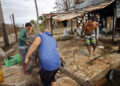 Unas personas recogen escombros tras el paso del huracán Rafael, en Playa Majana, en la provincia de Artemisa. Foto: Ernesto Mastrascusa / EFE.