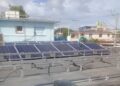 Un hombre desmonta paneles solares en un tejado de la Isla de la Juventud, horas antes del paso del huracán Rafael. Foto: Radio Caribe.