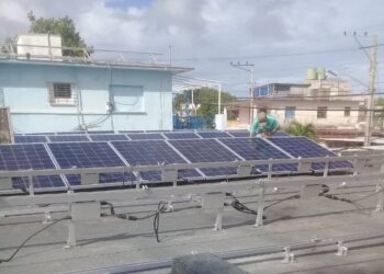 Un hombre desmonta paneles solares en un tejado de la Isla de la Juventud, horas antes del paso del huracán Rafael. Foto: Radio Caribe.