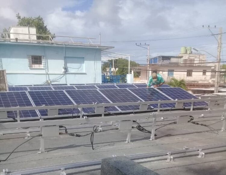 Un hombre desmonta paneles solares en un tejado de la Isla de la Juventud, horas antes del paso del huracán Rafael. Foto: Radio Caribe.