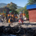 Personas pasan frente a los restos de una hoguera donde incineraron a un pandillero, en una calle de Puerto Príncipe. Foto: Johnson Sabin/EFE.