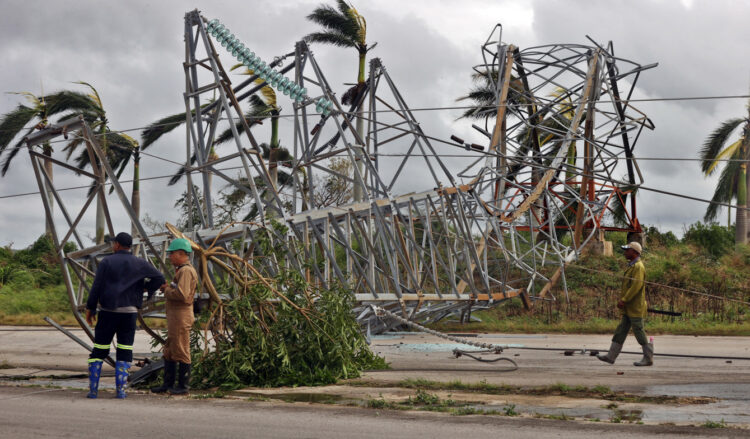 Trabajadores junto a una torre de energía caída tras el paso del huracán Rafael. Foto: Ernesto Mastrascusa/EFE.