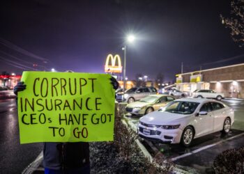 Una mujer que no quiso ser identificada y que trabaja en la industria de la salud, sostiene un cartel de protesta en las afueras del McDonald's donde el Departamento de Policía arrestó a Luigi Mangione, acusado de asesinar a un alto ejecutivo de las aseguradoras en la ciudad de Nueva York. Foto: EFE/EPA/CAMERON CROSTON.