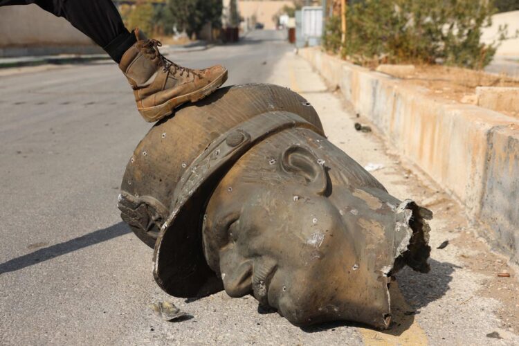 Un combatiente de la oposición pisa la estatua decapitada del fallecido presidente sirio Hafez Al Asad (padre de Bashar Al Asad) en el aeropuerto militar de Mezzeh en Damasco. Foto: EFE/EPA/MOHAMMED AL RIFAI.