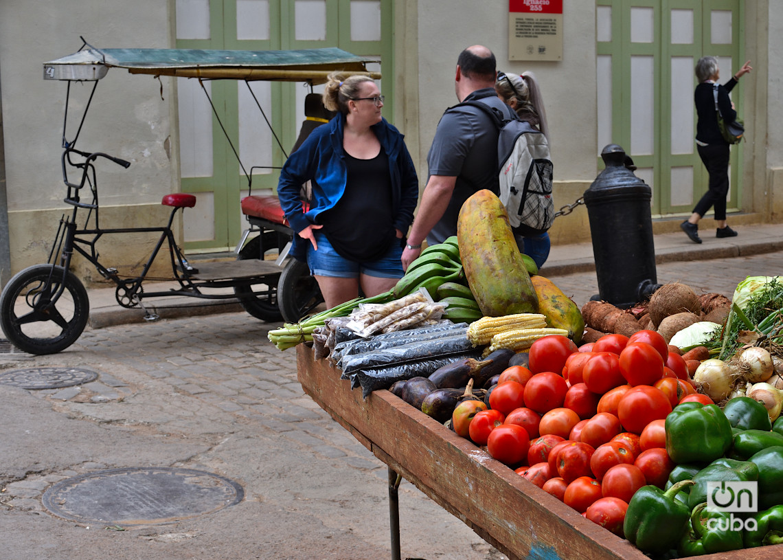 Turistas cerca de una carretilla de venta de productos agrícolas en la Calle Lamparilla y San Ignacio, en el centro histórico de La Habana, en los primeros días de 2025. Foto: Otmaro Rodríguez.