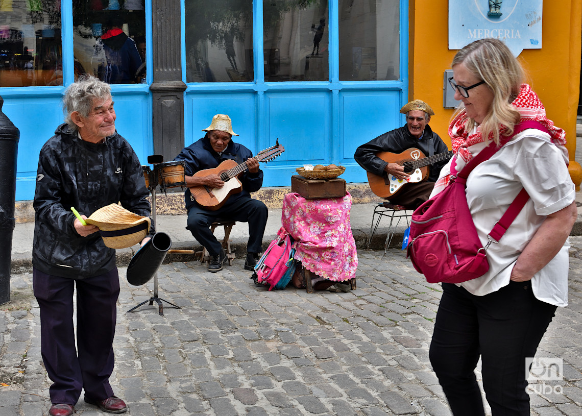 Músico callejero le pide una contribución a una turista para él y sus compañeros, en el centro histórico de La Habana. Foto: Otmaro Rodríguez.