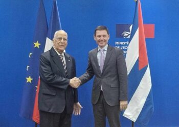 El viceprimer ministro cubano Ricardo Cabrisas (i) y Bertrand Dumont, presidente del Club de París, se saludan tras la firma de un nuevo acuerdo para reprogramar el pago de la deuda de Cuba con ese grupo de países acreedores. Foto: @EmbaCubaFrancia / X.