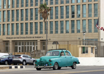 Un auto clásico de fabricación norteamericana, pasa frente a la embajada de Estados Unidos en La Habana. Foto: Ernesto Mastrascusa / EFE.