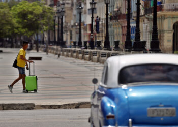 Un hombre con una maleta camina por el paseo del Prado, en La Habana. Foto: Ernesto Mastrascusa/EFE.